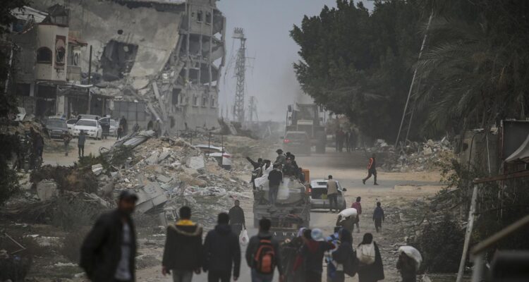 Palestinos caminan entre escombros en medio del alto al fuego entre Israel y Hamás, en Rafah
