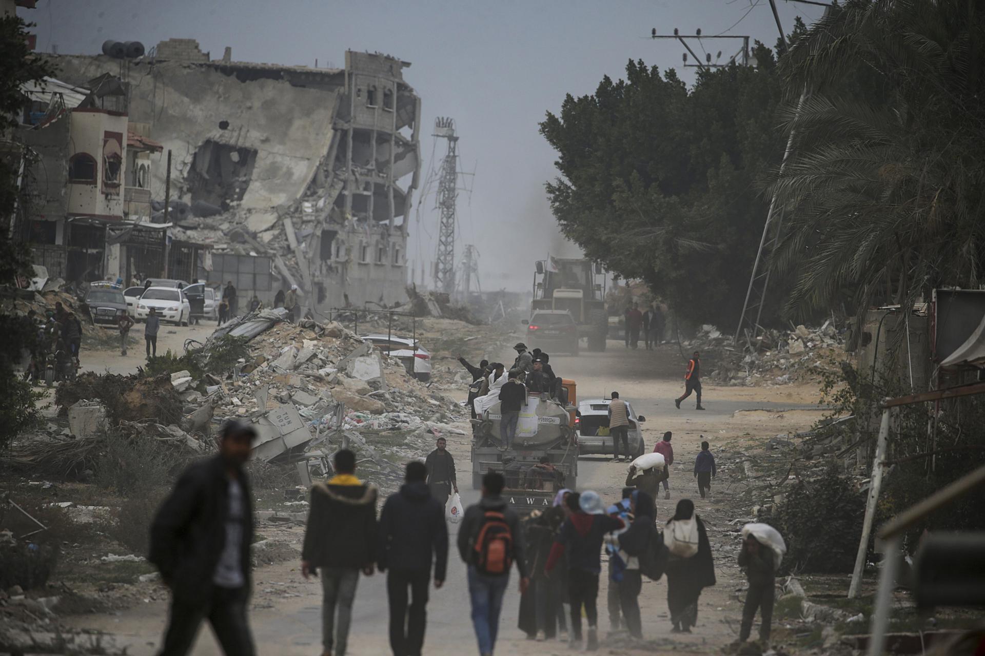 Palestinos caminan entre escombros en medio del alto al fuego entre Israel y Hamás, en Rafah