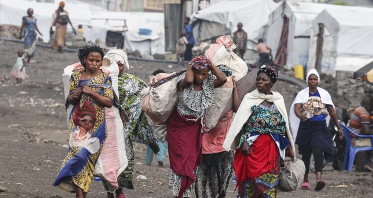 desplazados internos llegan con sus pertenencias a un asentamiento improvisado en el campamento de Lushagala en Goma