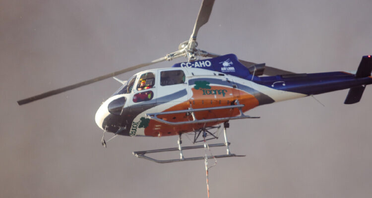 Brigadistas de Conaf y helicóptero combaten incendio cercano a viviendas en sector rural de Chonchi