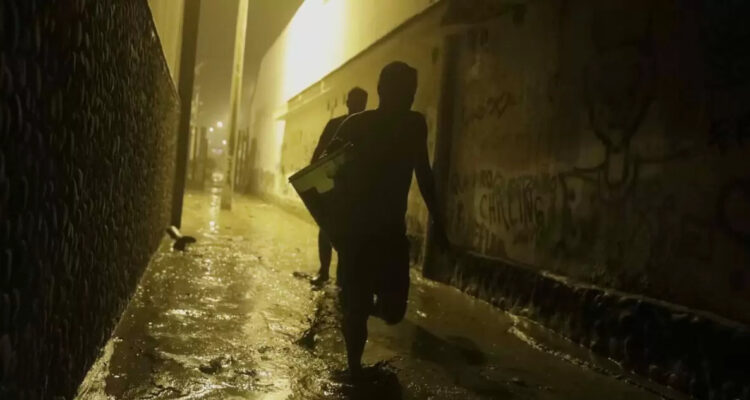Sombras en medio de callejón bajo la lluvia.