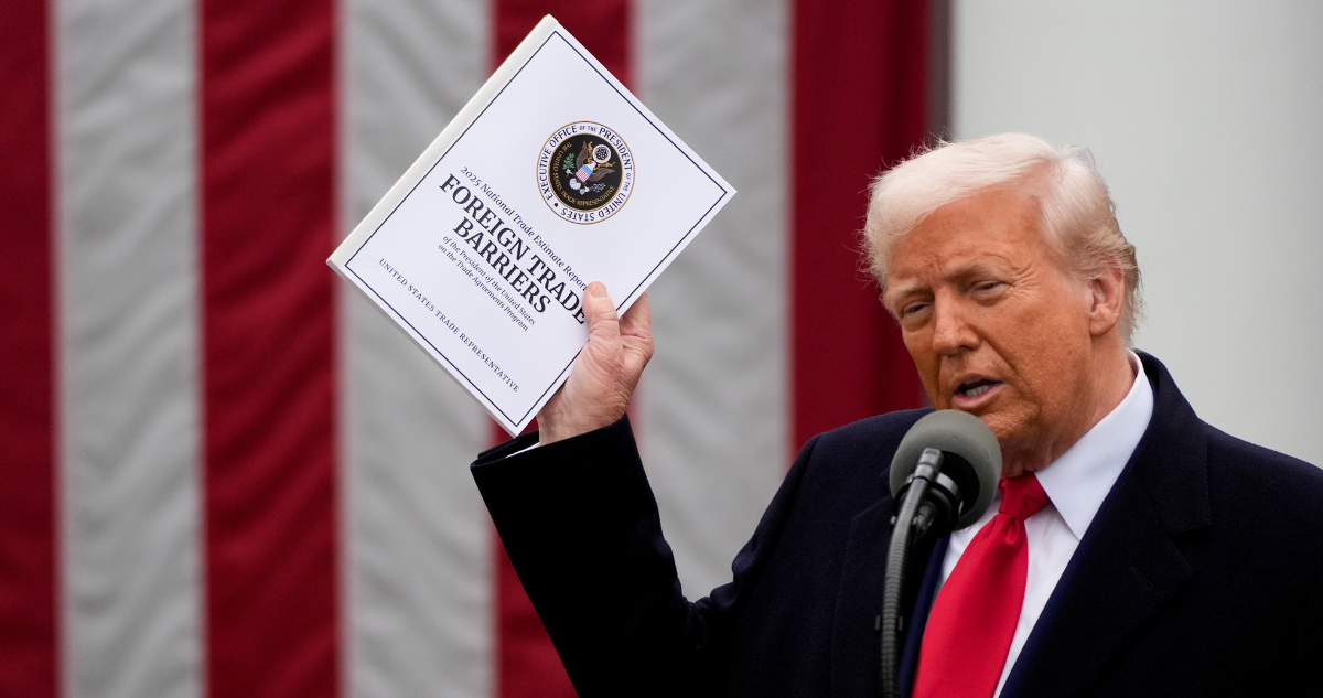 Donald Trump con carpeta de aranceles, bandera de Estados Unidos atrás.