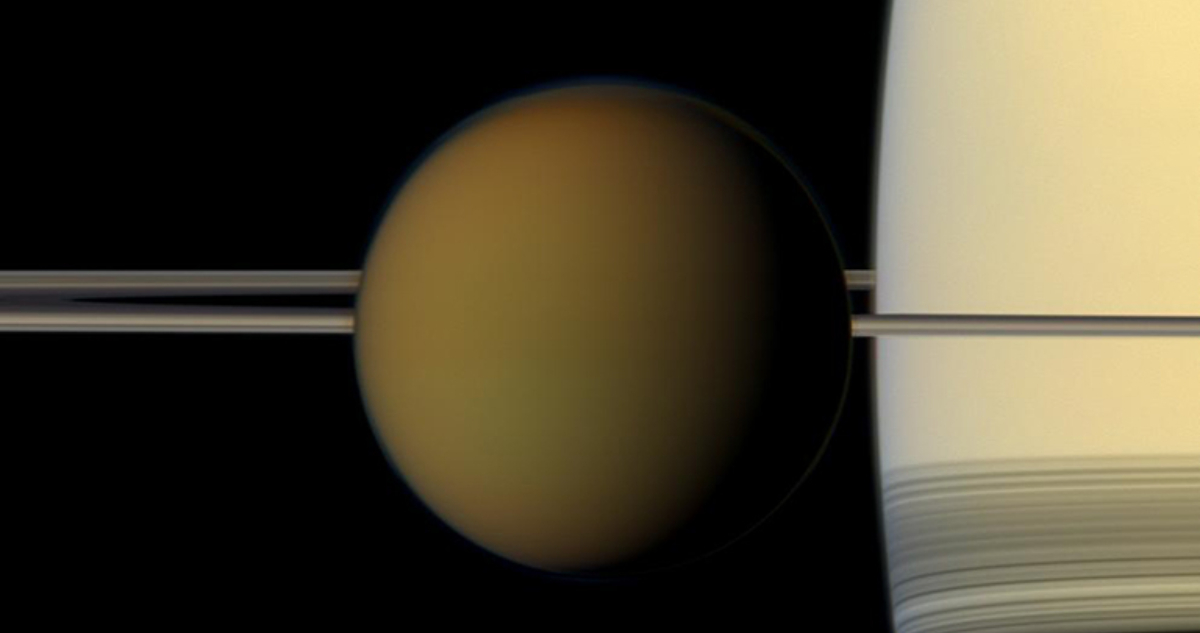 Titán, pasa frente al planeta y sus anillos en esta instantánea en color real de la nave espacial Cassini de la NASA.