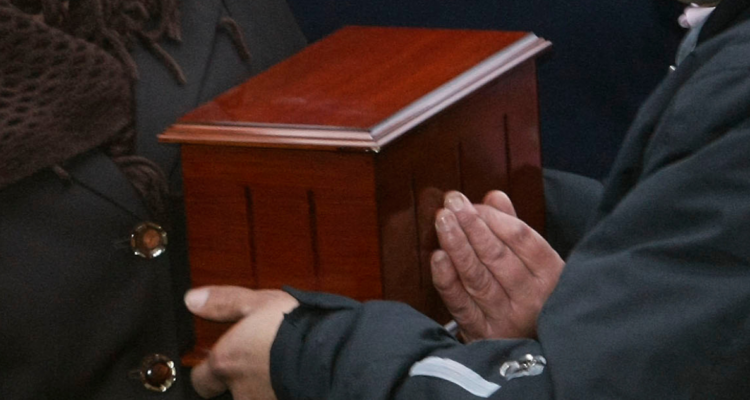 Familia sosteniendo urna tras cremación en funeral
