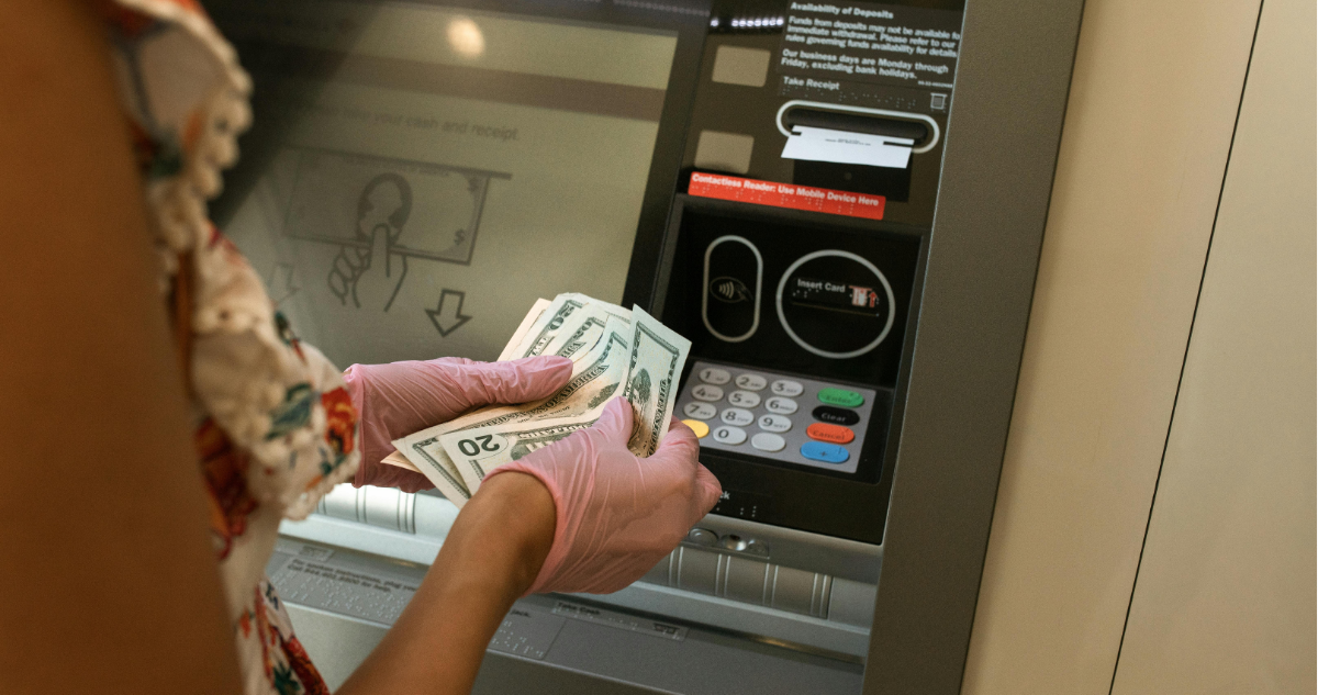 Mujer sacando dinero de cajeros automáticos en referencia a botón para evitar estafas