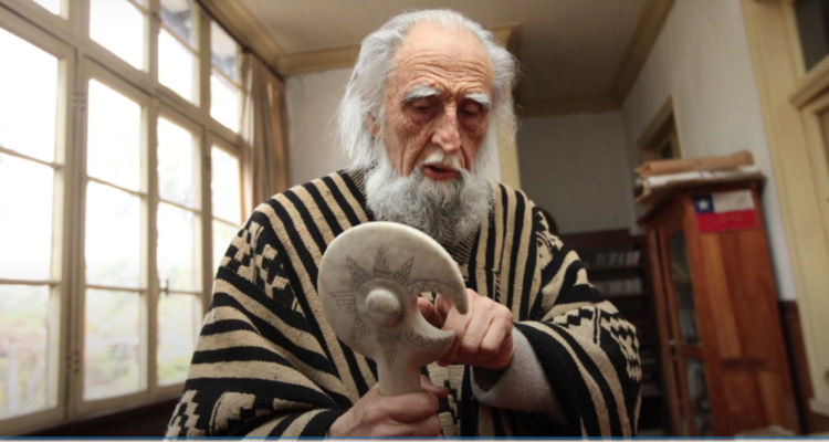 Gastón Soublette sosteniendo escultura mapuche del calendario lunar