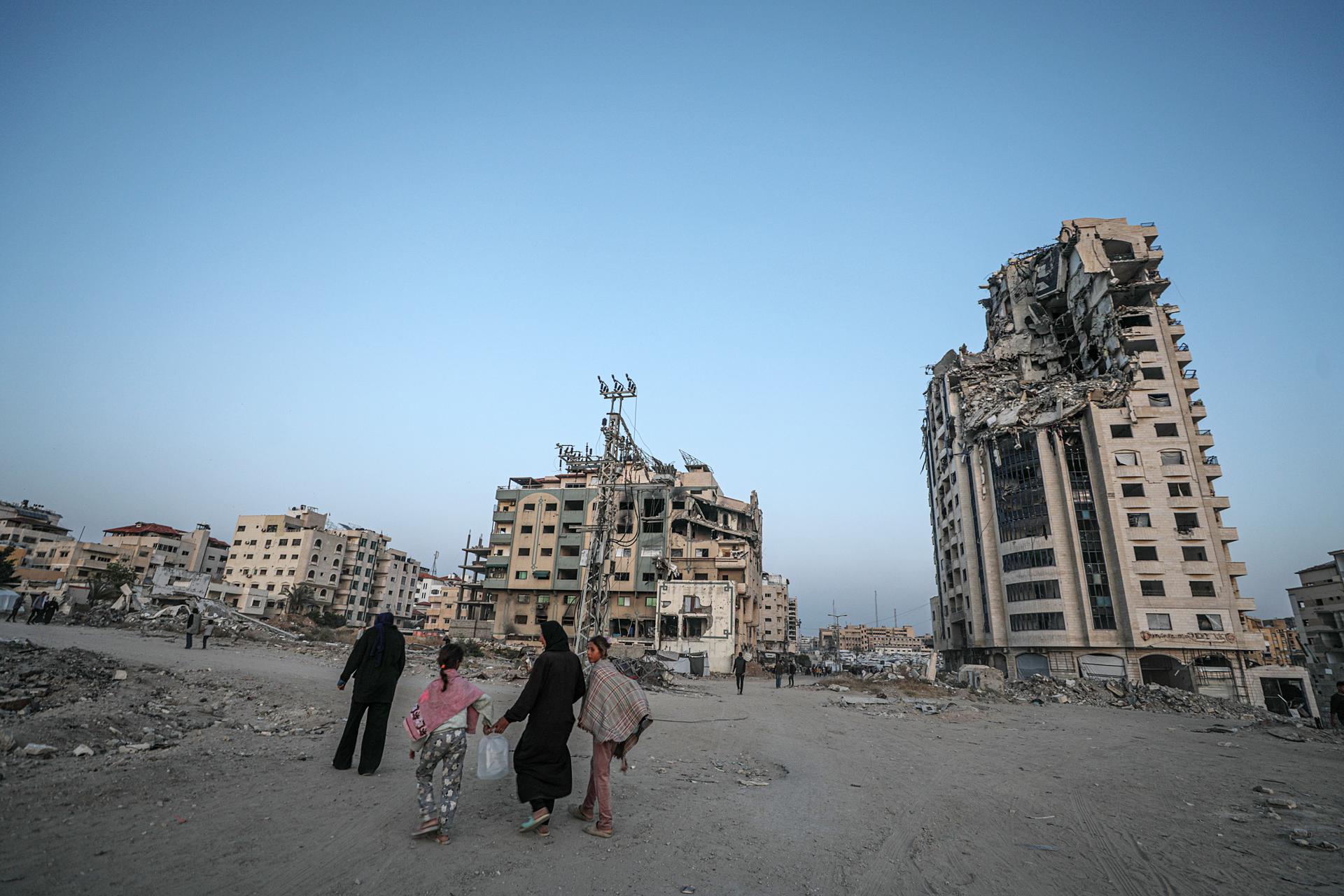 Desplazados internos caminan entre edificios destruidos en Gaza