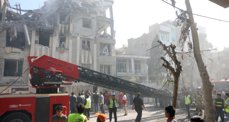 Bomberos y rescatistas trabajan alrededor de un edificio alcanzado por ataques aéreos israelíes en Teherán