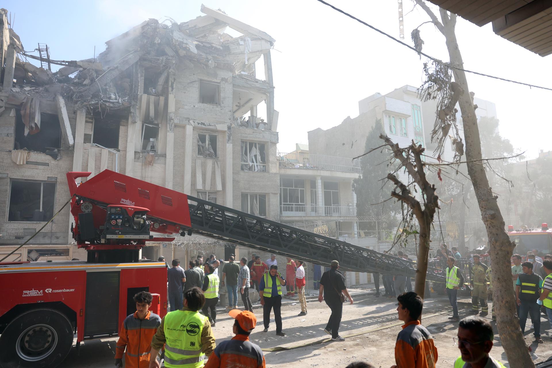 Bomberos y rescatistas trabajan alrededor de un edificio alcanzado por ataques aéreos israelíes en Teherán