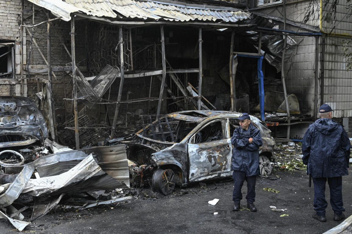 
Agentes de la policía ucraniana junto a vehículos destruidos en el lugar de un ataque ruso en una zona residencial de Kiev