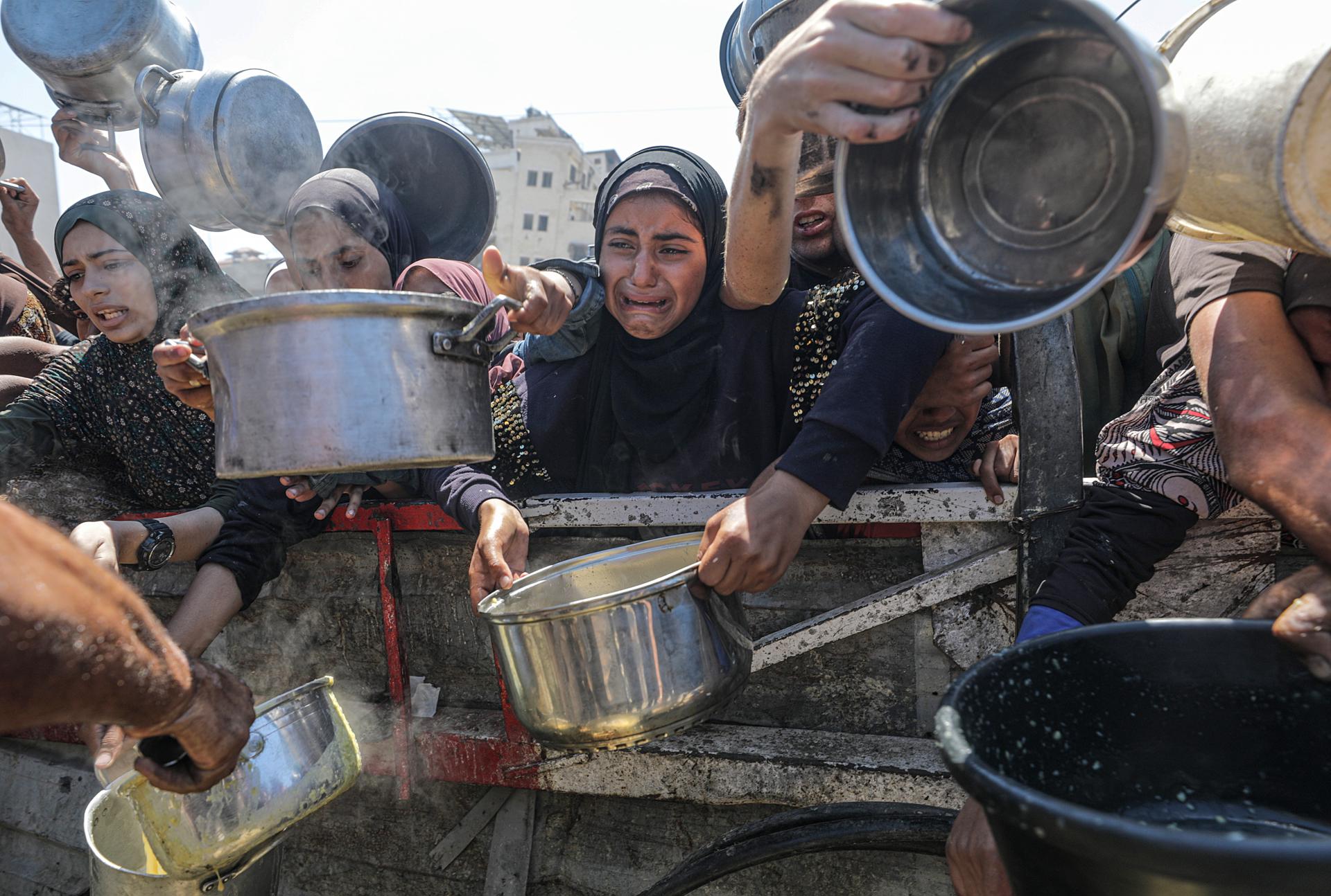 Palestinos desplazados, incluidos niños, reciben comida de una cocina benéfica en la ciudad de Gaza
