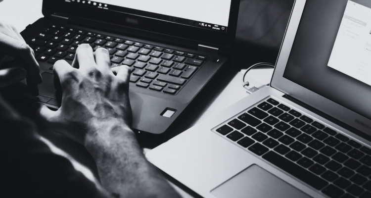 Persona escribiendo en computadores para columna sobre la maquinaria de la mentira