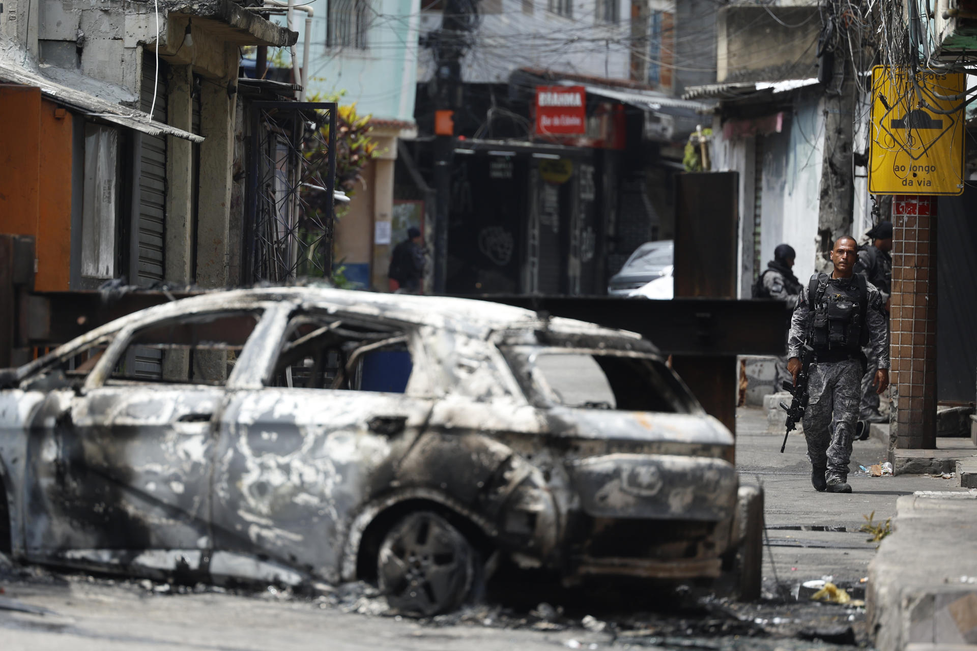 Un policía de Río de Janeiro camina junto a un vehículo quemado
