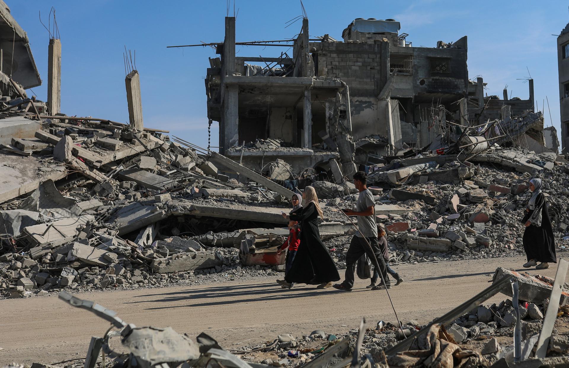 Palestinos caminan junto a casas destruidas en la carretera Al Jalaa en la ciudad de Gaza,