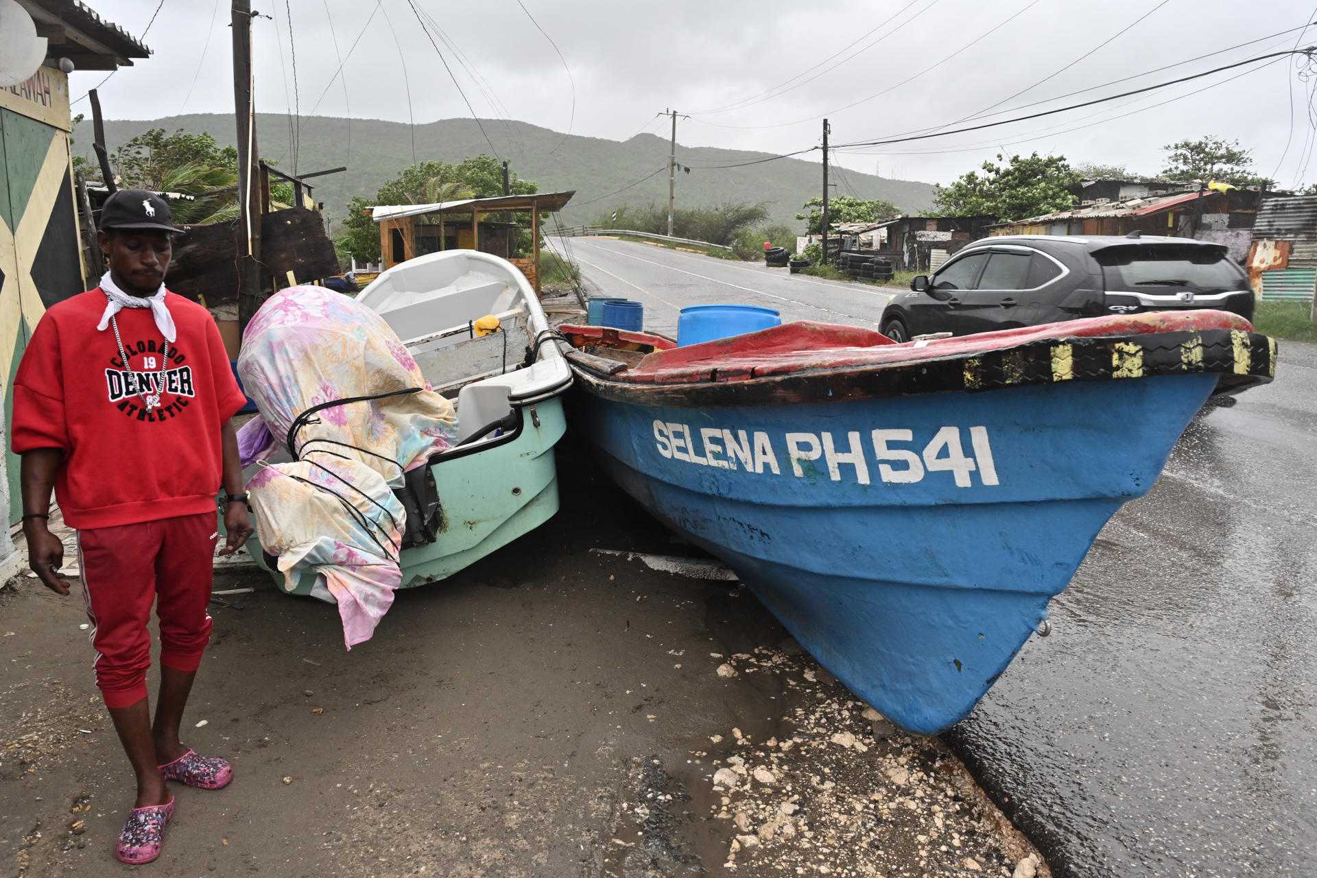 Un pescador cubre sus barcos ante el paso del huracán Melissa en la playa pesquera de Port Henderson, Jamaica 