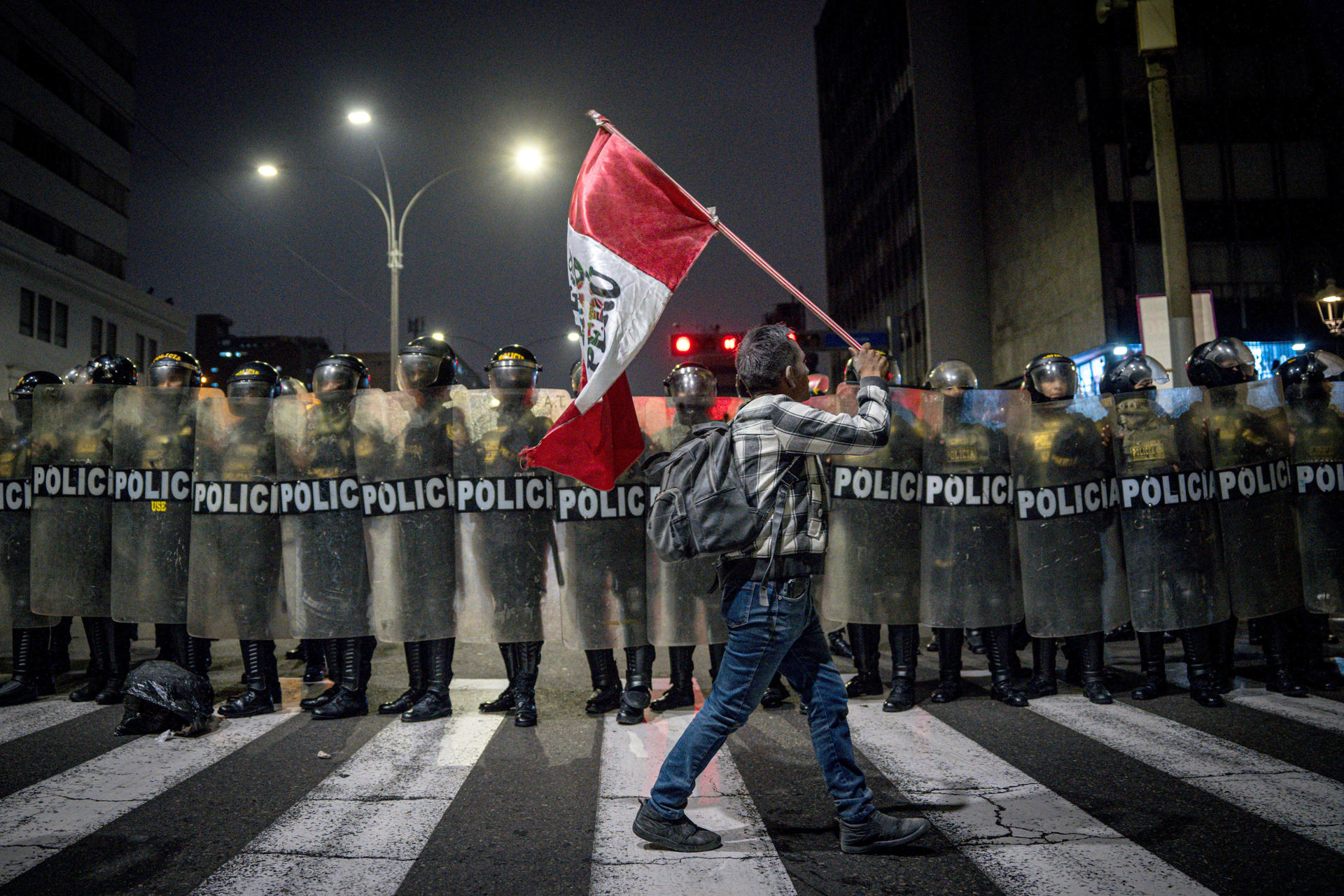 Una persona sostiene una bandera de Perú frente a la Policía el miércoles en Lima