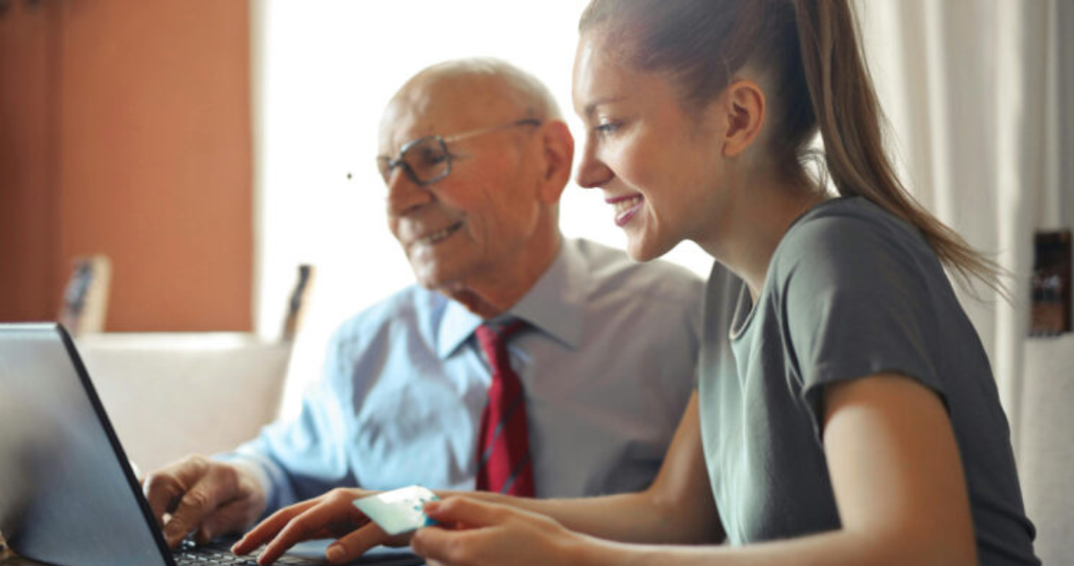 Persona mayor y joven trabajando en un computador. Foto de contexto para columna sobre políticas digitales