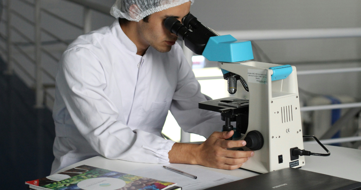 Foto de contexto de persona mirando un microscopio