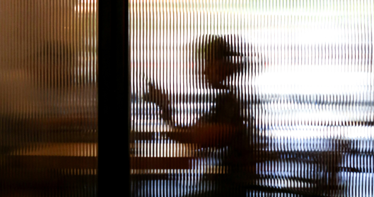 Foto de contexto de siluetas de personas tras un vidrio