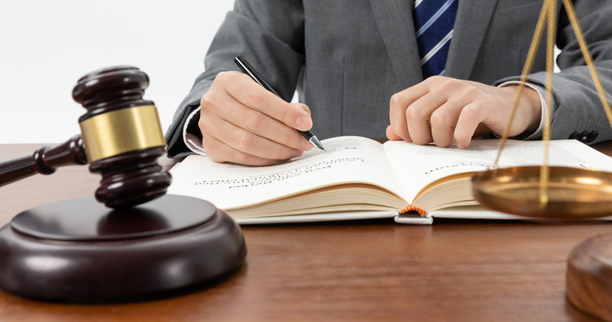 Imagen de contexto de balanza de justicia, martillo de juez y hombre escribiendo en un libro