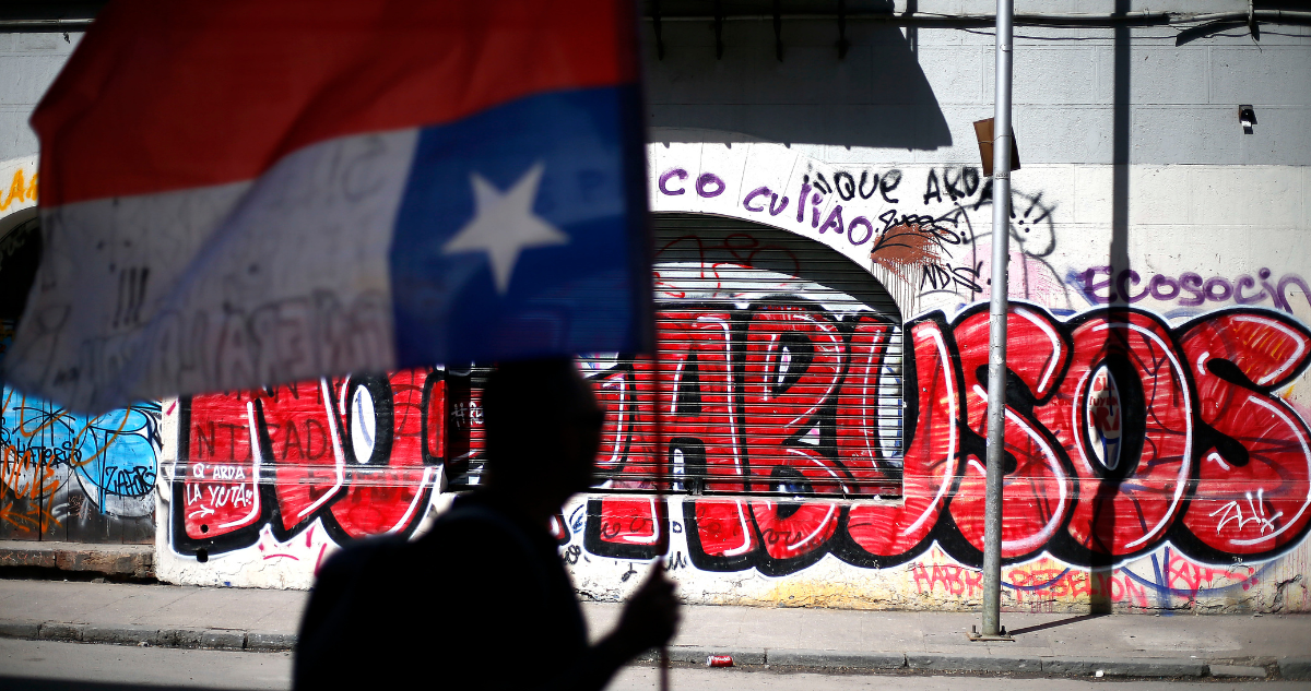 Foto de archivo del Estallido Social muestra paredes rayadas y un hombre caminando con la bandera de Chile al revés