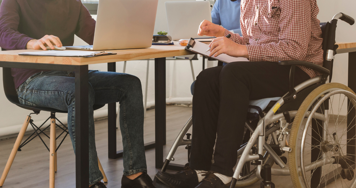 Inclusión laboral. Tres personas trabajando en una oficina. Una de ellas está en silla de ruedas.