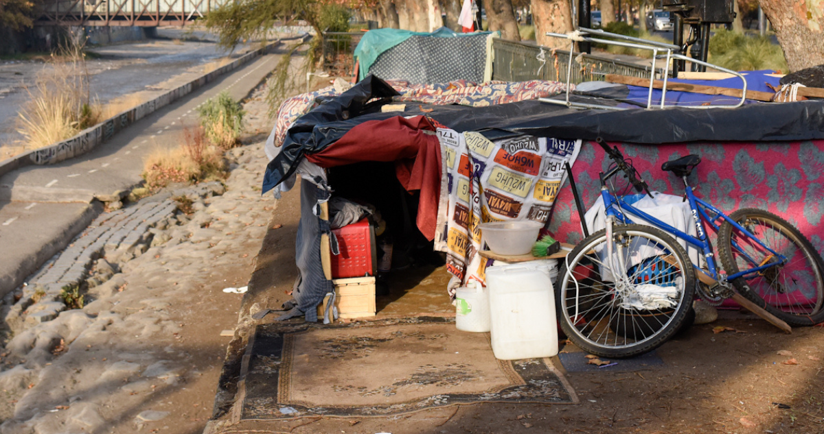 Foto de contexto de vivienda de personas en situación de calle improvisada al lado de un río
