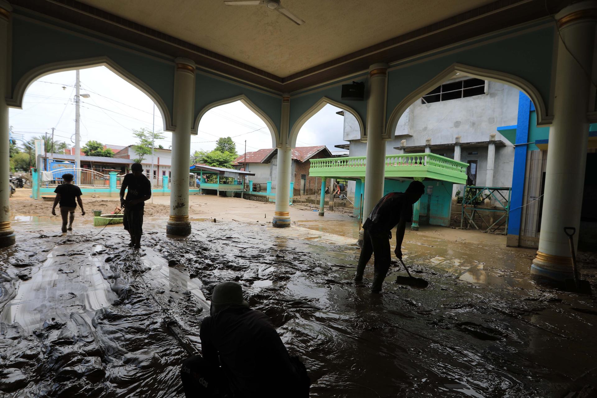 Residentes ayudan a limpiar una mezquita en un pueblo afectado por las inundaciones en el área de Meureudu, Indonesia