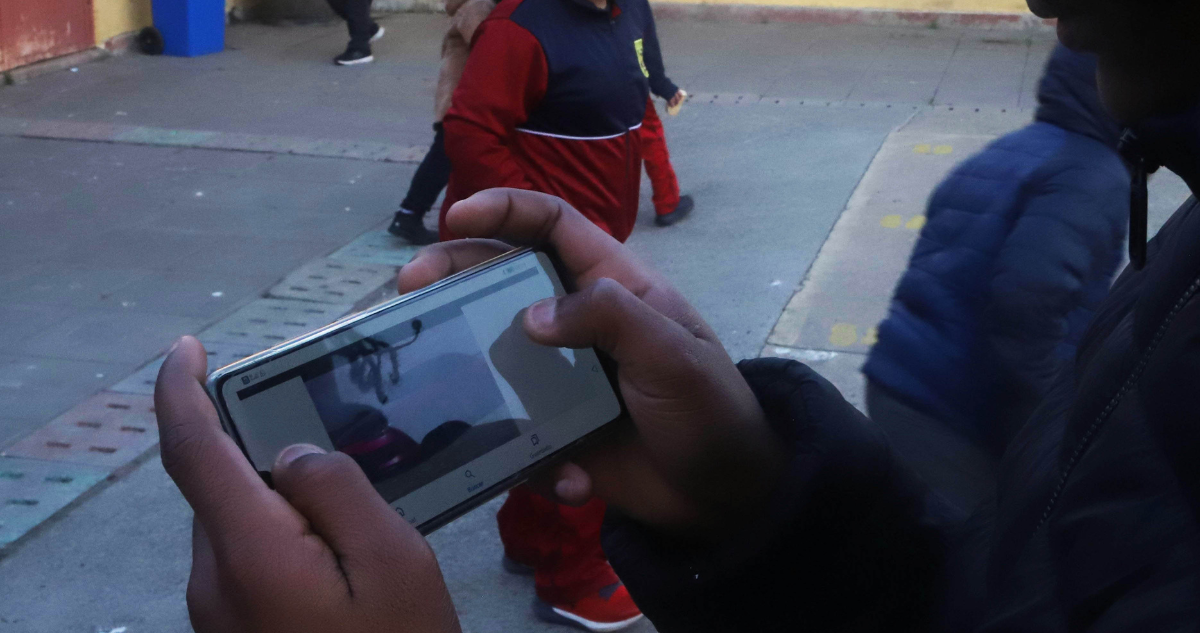 Niño con un celular en el patio de un colegio