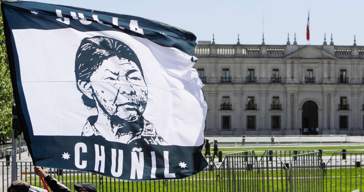 Personas portando bandera con rostro de Julia Chuñil en protesta.