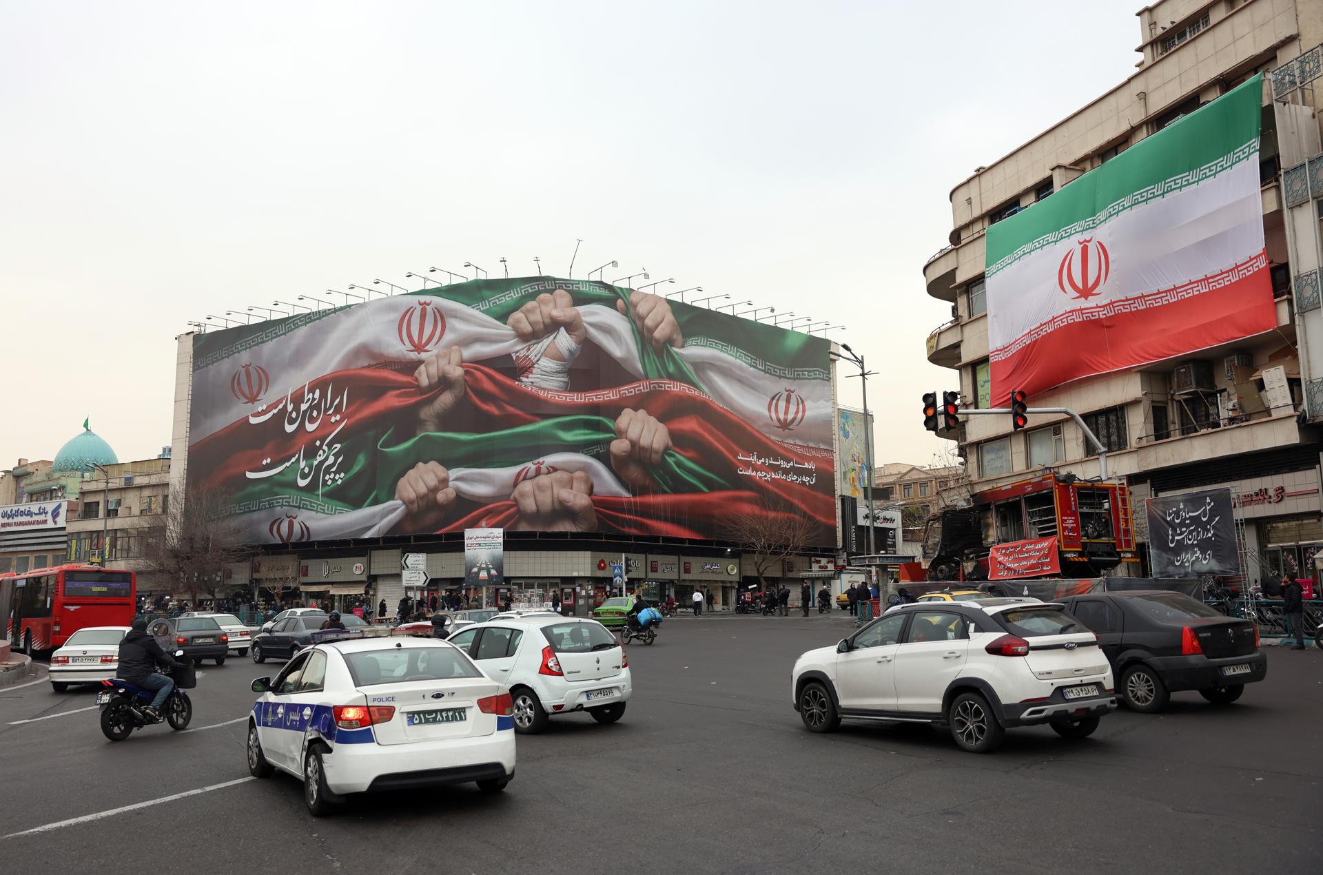 Iraníes pasan frente a un cartel que dice “Irán es nuestra patria” en Teherán