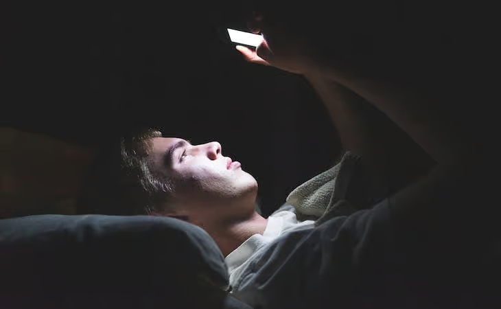 Joven usando su teléfono móvil por la noche