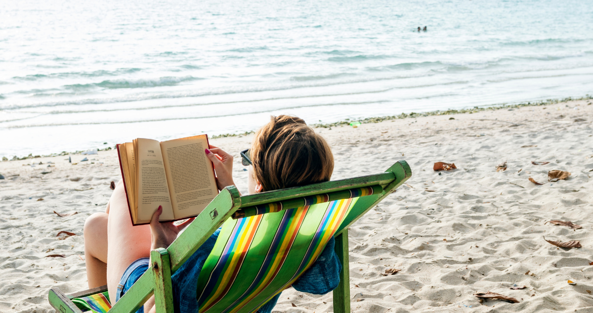 Persona sola en la playa leyendo un libro