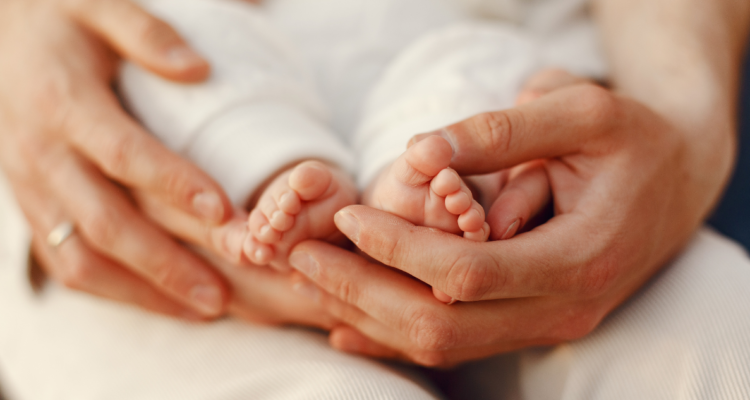 Manos de una mamá tomando los pies de su bebé