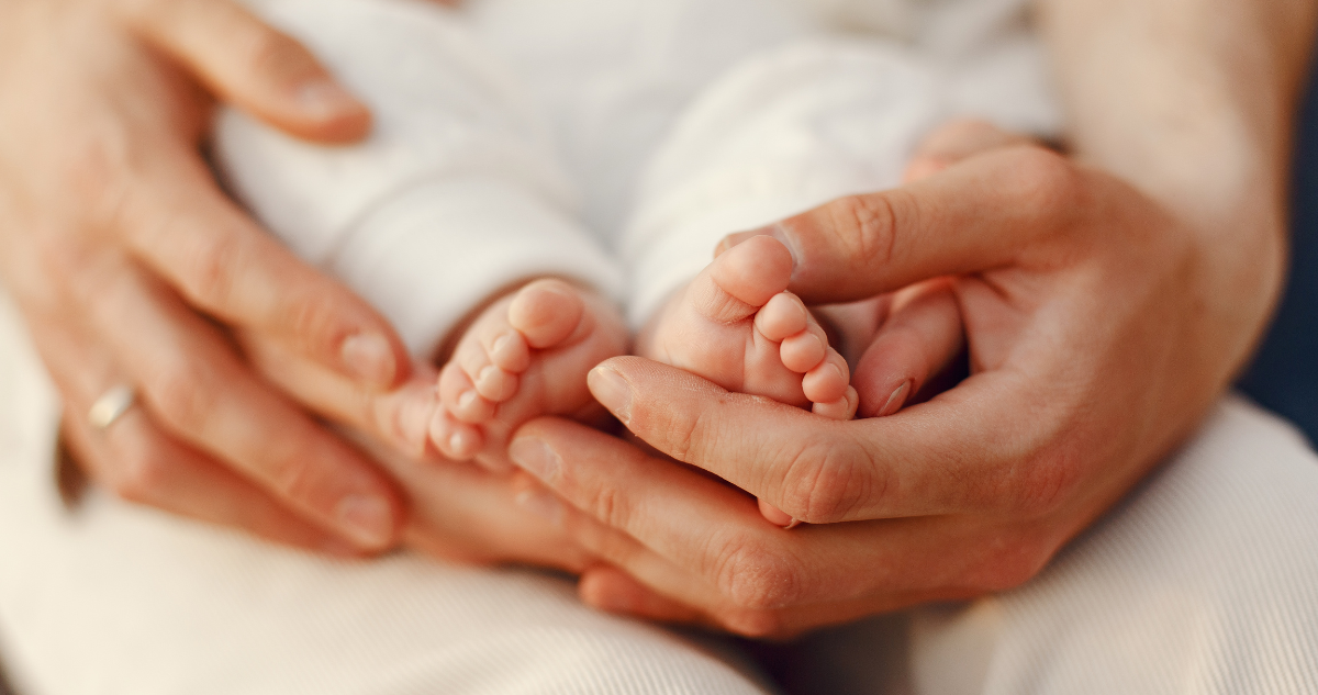 Manos de una mamá tomando los pies de su bebé
