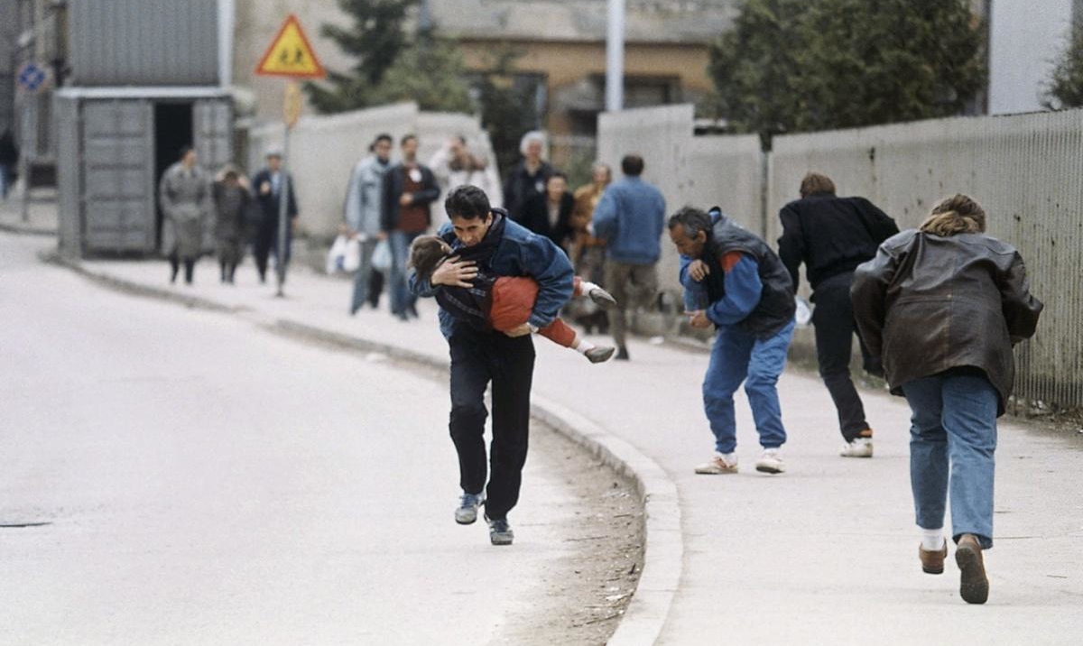 Un hombre carga a su hija mientras se refugia de los francotiradores en Sarajevo