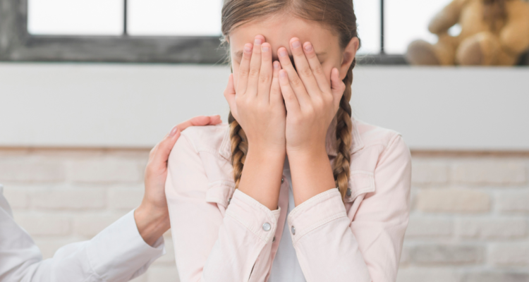 Niña cubriéndose el rostro