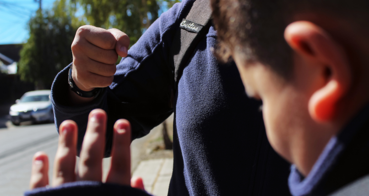 Foto de contexto de niños con uniforme peleando (no se ven los rostros).