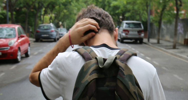 Niño con mochila caminando con actitud de fracaso o tristeza.