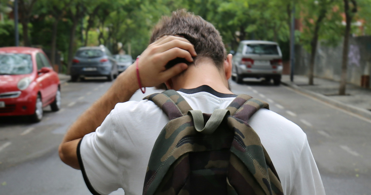 Niño con mochila caminando con actitud de fracaso o tristeza.