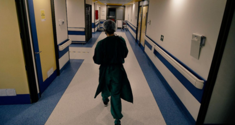 Personal de salud caminando por pasillo de hospital.