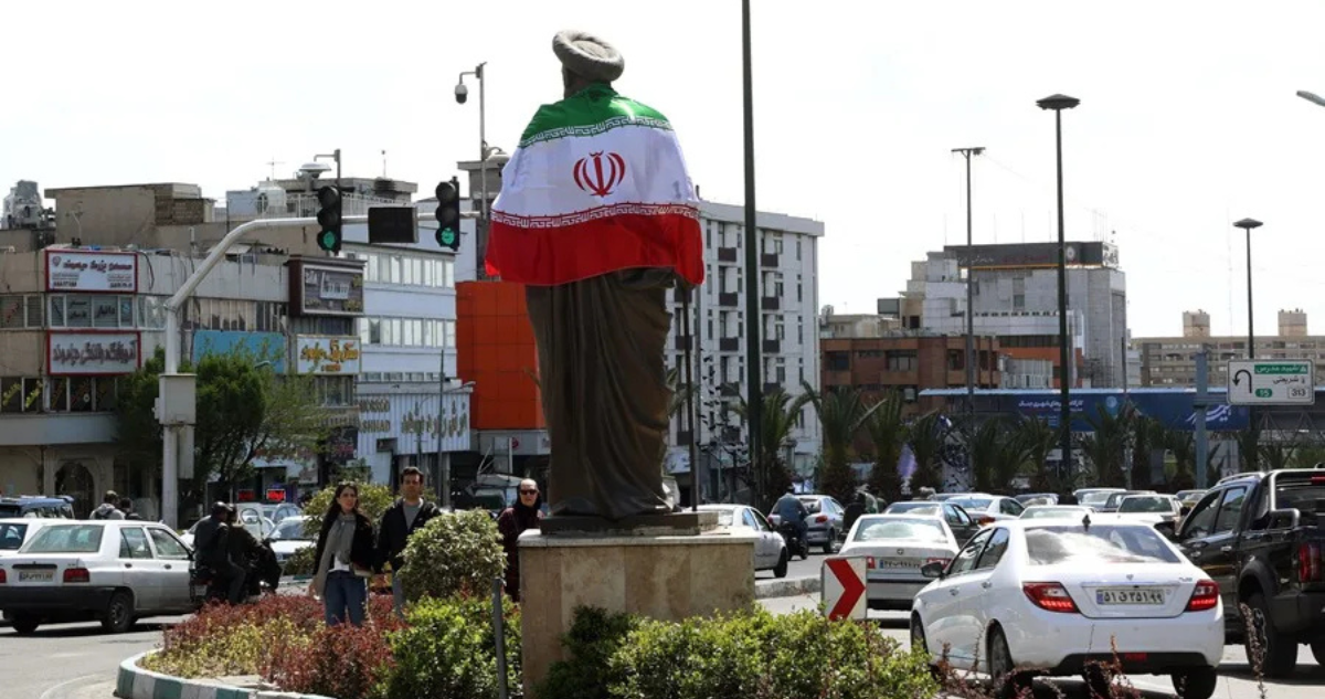 La bandera nacional de Irán rodea una estatua en una calle de Teherán