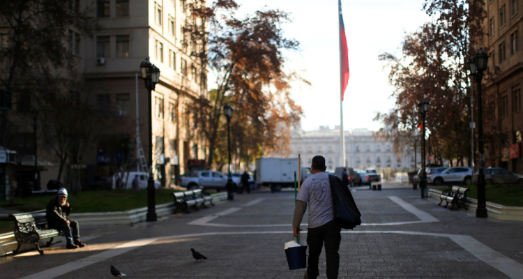 Persona caminando por calles de Santiago. Bandera chilena de fondo.
