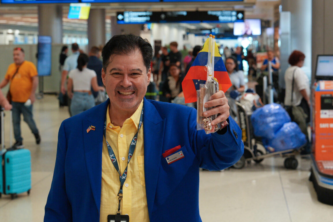 Un empleado del American Airlines saluda con banderas venezolanas a los pasajeros del vuelo