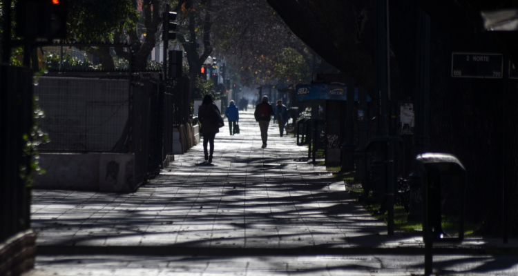 Personas caminando en sombras por una calle de Chile.