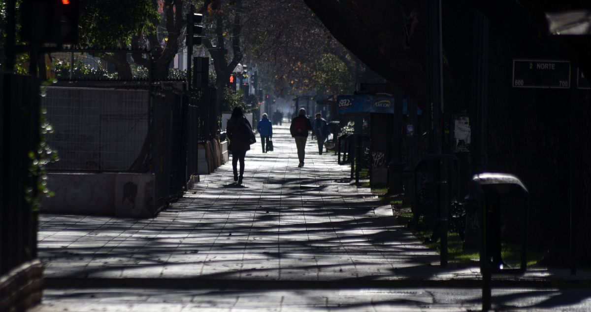 Personas caminando en sombras por una calle de Chile.