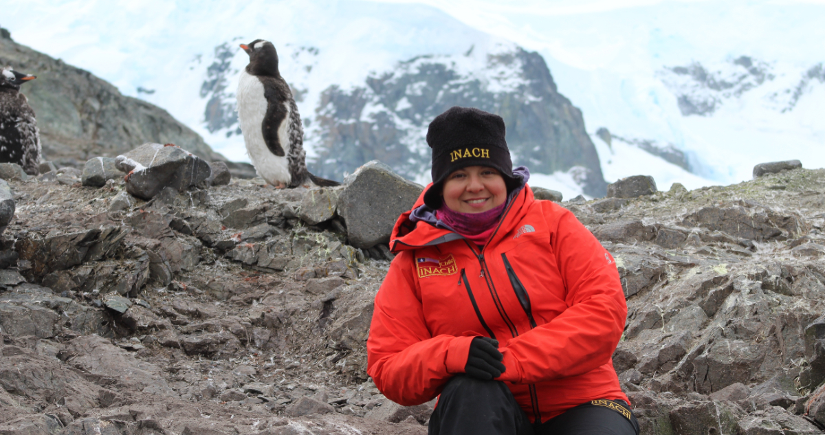 Foto de la Dra. Daly Noll junto a un pingüino