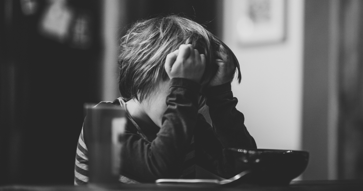 Niño triste cubriéndose el rostro