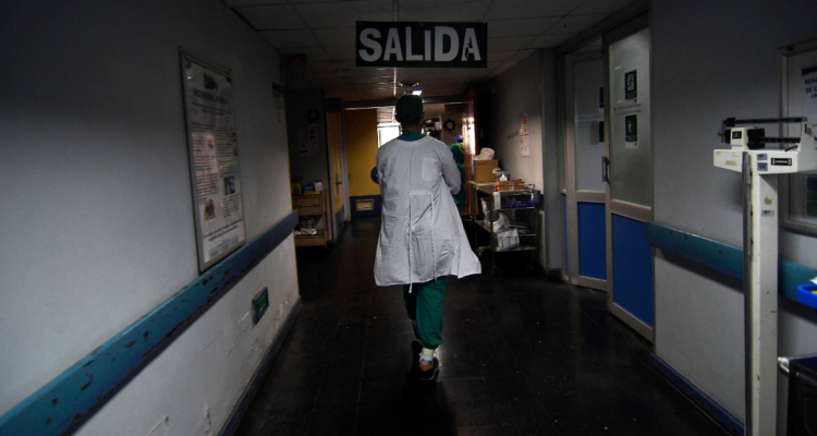 Personal de salud pública caminando por pasillo de hospital.