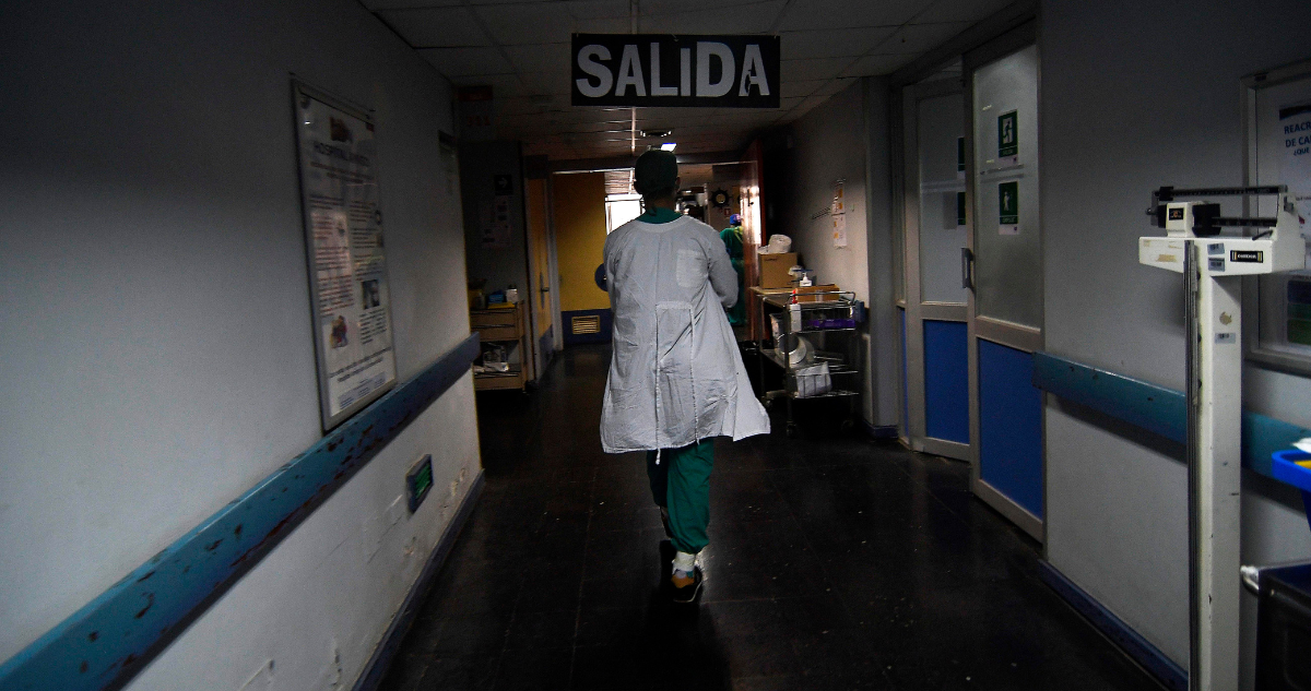 Personal de salud pública caminando por pasillo de hospital.